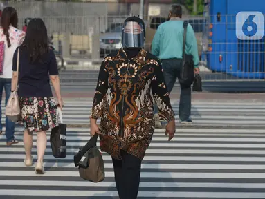 Seorang wanita yang mengenakan baju batik berjalan di kawasan Thamrin Sudirman, Jakarta, Jumat (2/10/2020). Pada Hari Batik Nasional yang berlangsung di tengah pandemi COVID-19, sebagian masyarakat terlihat mengenakan baju dan masker dengan motif batik. (merdeka.com/Imam Buhori)