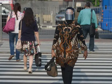 Seorang wanita yang mengenakan baju batik berjalan di kawasan Thamrin Sudirman, Jakarta, Jumat (2/10/2020). Pada Hari Batik Nasional yang berlangsung di tengah pandemi COVID-19, sebagian masyarakat terlihat mengenakan baju dan masker dengan motif batik. (merdeka.com/Imam Buhori)