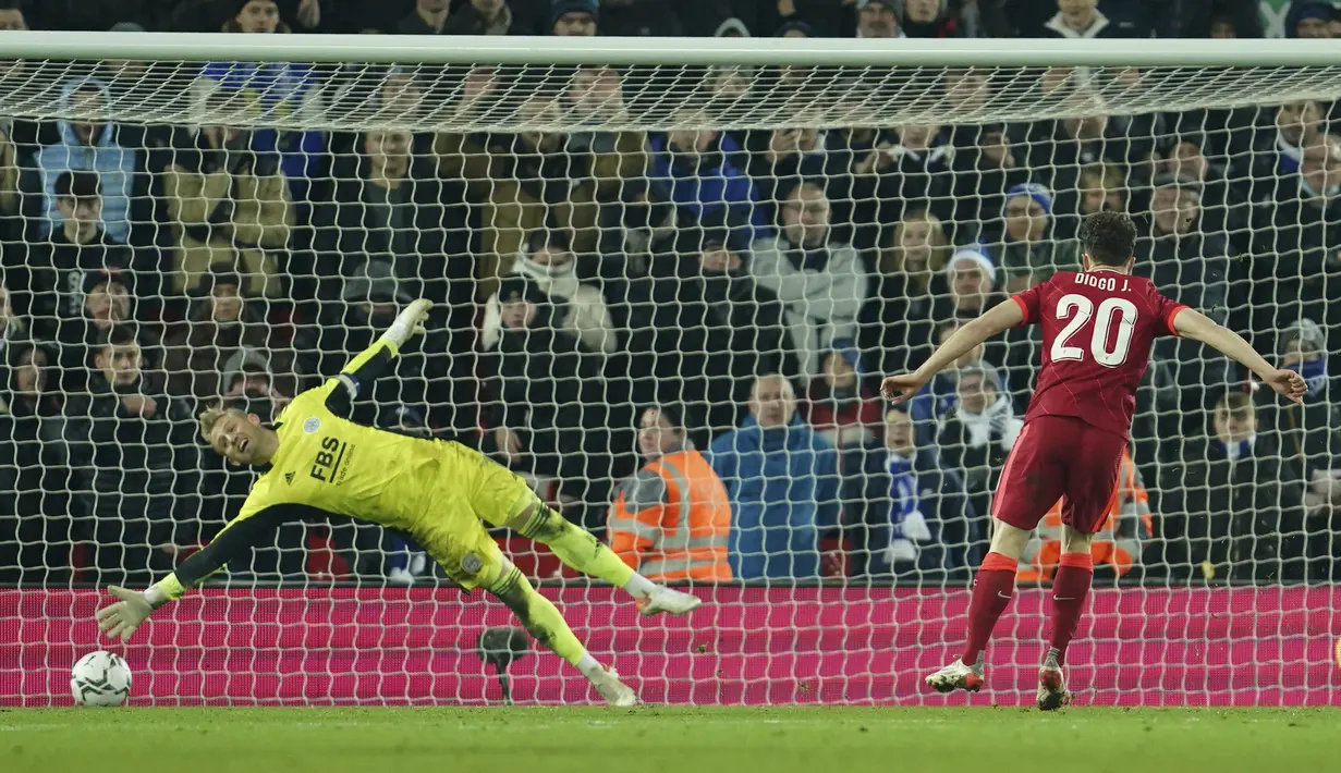 Penyerang Liverpool, Diogo Jota mencetak gol yang dijaga kiper Leicester City, Kasper Schmeichel pada adu penalti pertandingan perempat final Piala Liga Inggris di Stadion Anfield, Inggris, Kamis (22/12/2021). Liverpool menang adu penalti atas Leicester dengan skor 5-4. (AP Photo/Jon Super)