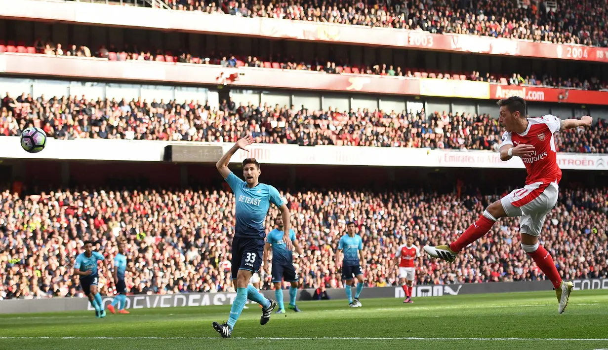 Aksi Mesut Ozil (kanan) mencetak gol saat Arsenal menang atas  Swansea City 3-2 pada laga Premier League pekan ke-8 di Emirates Stadium, London (15/10/2016). (AFP/Justin Tallis)