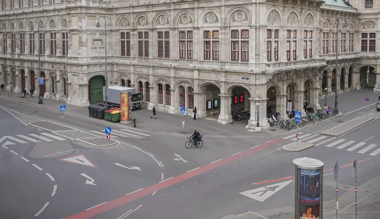 Seorang perempuan mengendarai sepeda di sepanjang jalan yang sepi di Wina, Austria, Senin (22/11/2021). Austria memberlakukan lockdown atau penguncian nasional Senin pagi untuk memerangi melonjaknya infeksi virus corona Covid-19. (AP Photo/Vadim Ghirda)