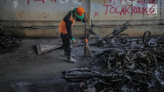 Petugas mengumpulkan bangkai sepeda motor yang dibakar massa aksi di bawah jembatan layang Slipi, Jakarta, Kamis (26/9/2019). Aksi menolak revisi UU KPK, revisi UU KUHP dan sejumlah revisi UU lainnya berjalan anarkis di sekitar Gedung DPR pada Rabu 25 September 2019. (Liputan6.com/Faizal Fanani)