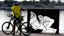 Pengendara sepeda mengabadikan gambar patung erotis karya seniman Antoni Miro yang dipamerkan di pelabuhan Valencia, Spanyol (19/9). (AFP Photo/Jose Jordan)