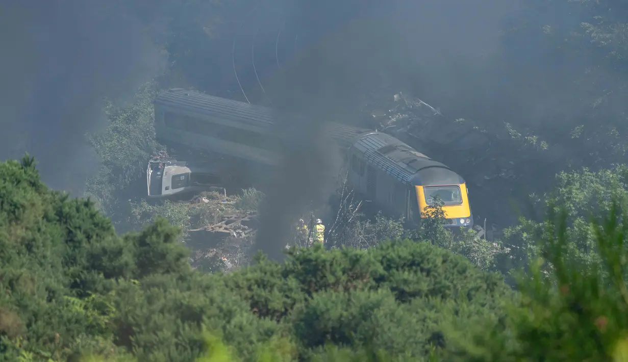 Personel layanan darurat terlihat di lokasi kecelakaan kereta api dekat Stonehaven di timur laut Skotlandia (12/8/2020). Kecelakaan tersebut telah menewaskan tiga orang dan belasan luka-luka setelah kereta penumpang tergelincir. (AFP/MICHAL WACHUCIK)