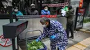 Seorang warga menerima sayuran di atas gerbang di Wuhan di provinsi Hubei tengah China (3/3/2020). Sejauh ini, total 80.026 kasus virus corona terkonfirmasi di wilayah China daratan. (AFP/STR)