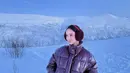 Lyodra mengenakan penutup telinga maroon dipadukan jaket padding model pendeknya. Dipadukan bawahan celana hitam. [@lyodraofficial]