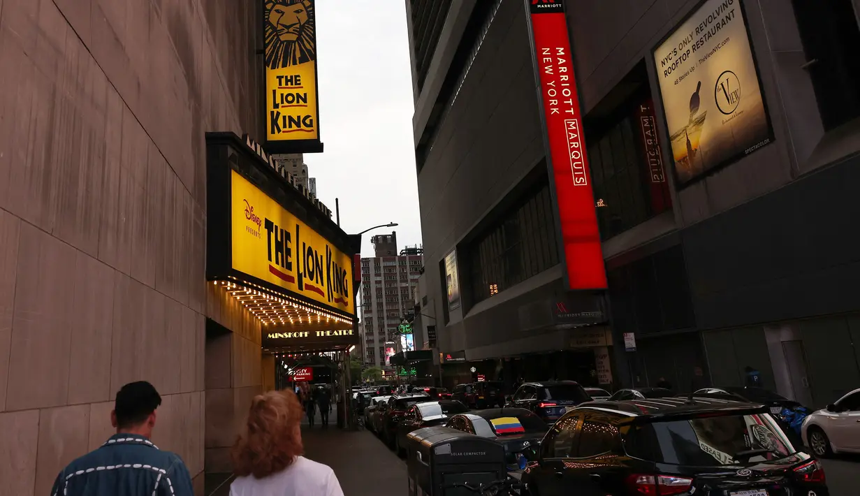 Orang-orang berjalan melewati Theater District di Manhattan, New York City, Kamis (6/5/2021). Gubernur Andrew Cuomo mengumumkan teater Broadway akan dibuka kembali dalam kapasitas penuh mulai 14 September, sejak ditutup Maret 2020 karena pandemi COVID-19. (MICHAEL M. SANTIAGO/GETTY IMAGES VIA AFP)