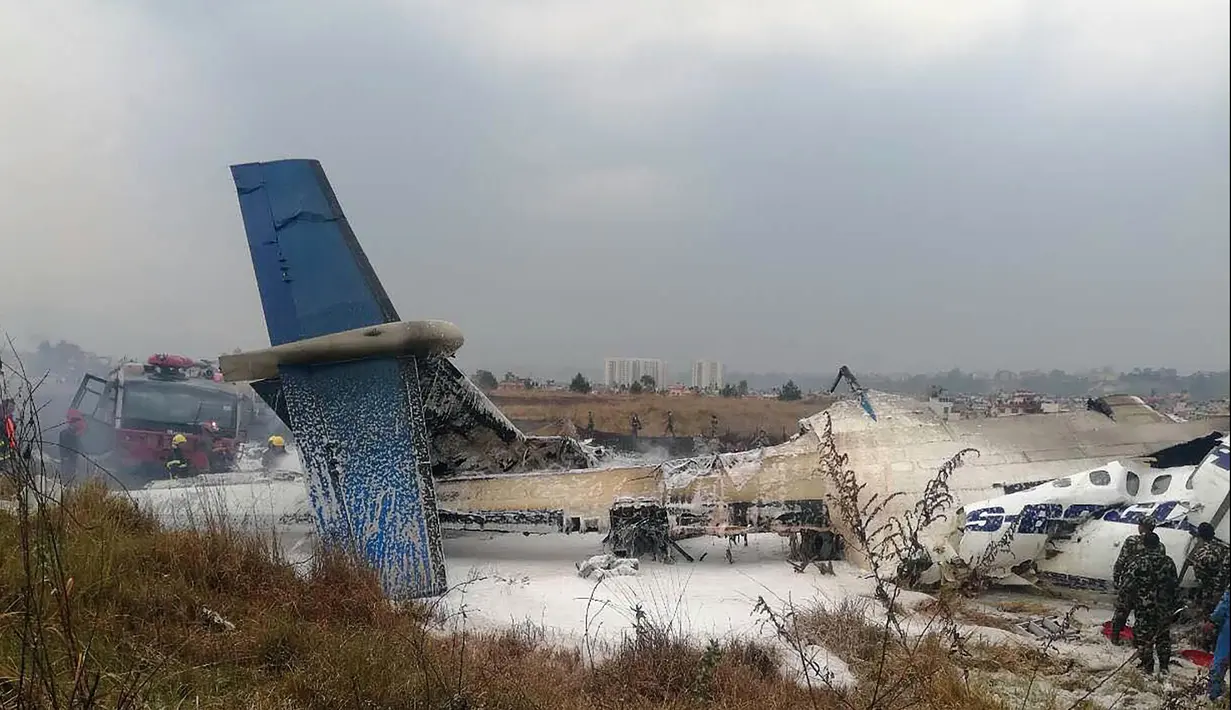 Tim penyelamat berkumpul di sekitar puing pesawat yang jatuh di dekat Bandara Internasional Kathmandu, Nepal, Senin (12/3). Kecelakaan ini merupakan bencana penerbangan terburuk yang melanda Nepal selama bertahun-tahun. (Saroj BASNET/AFP)