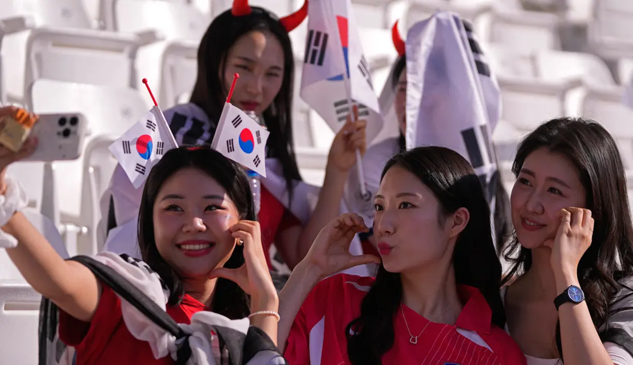 Suporter Korea Selatan berfoto bersama saat menunggu dimulainya pertandingan sepak bola Grup E Piala Asia antara Korea Selatan dan Bahrain di Stadion Jassim Bin Hamad, Doha, Qatar, Senin (15/1/2024). (AP Photo/Thanassis Stavrakis)