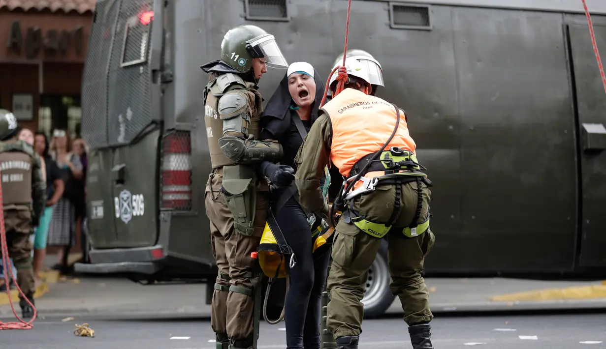 Seorang aktivis wanita mengenakan pakaian seperti biarawati diamankan polisi setempat setelah ia melakukan aksi protes dan memasang sepanduk pro-aborsi jelang kedatangan Paus Fransiskus di Chili (15/1). (AP Photo / Victor R. Caivano)