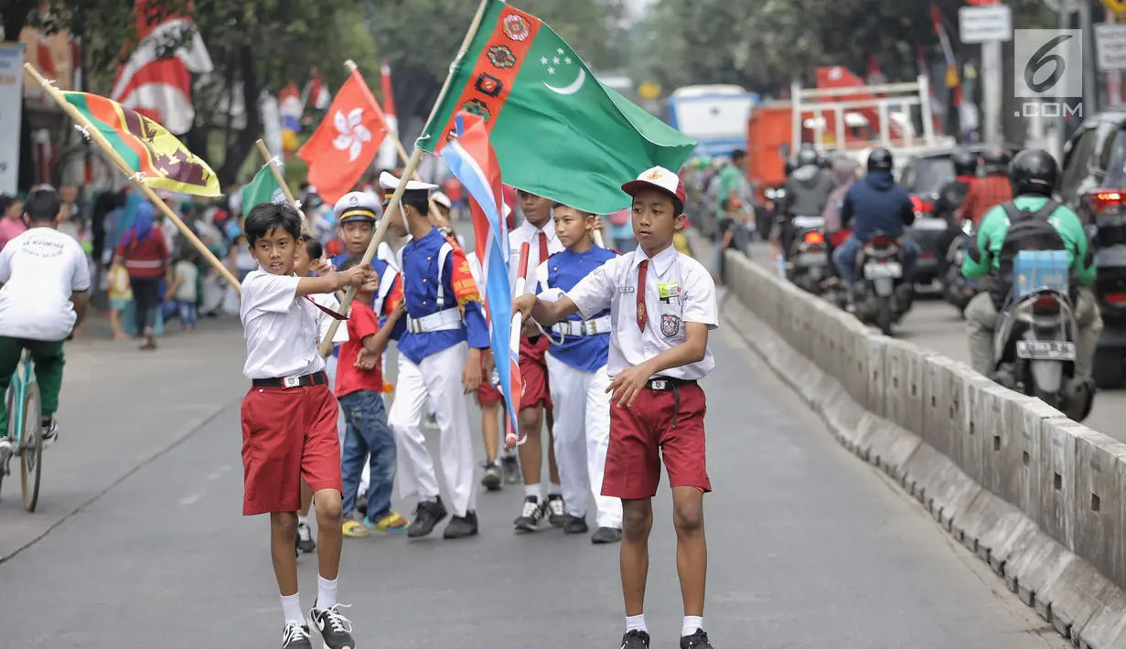 Siswa-siswi SD membawa bendera negara peserta Asian Games 2018 untuk menyambut Kirab Obor di kawasan Jati Padang, Pasar Minggu, Rabu (15/8). Mereka memenuhi jalanan untuk menyaksikan langsung Pawai Obor Asian Games 2018. (Liputan6.com/Faizal Fanani)