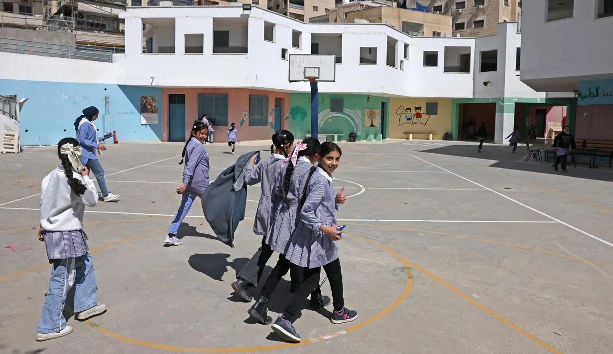 Siswi-siswi sekolah Palestina berjalan-jalan di taman bermain sekolah yang dikelola Badan PBB untuk pengungsi Palestina (UNRWA) di kamp pengungsi Shuafat, Yerusalem timur pada 6 Mei 2025. (AHMAD GHARABLI/AFP)