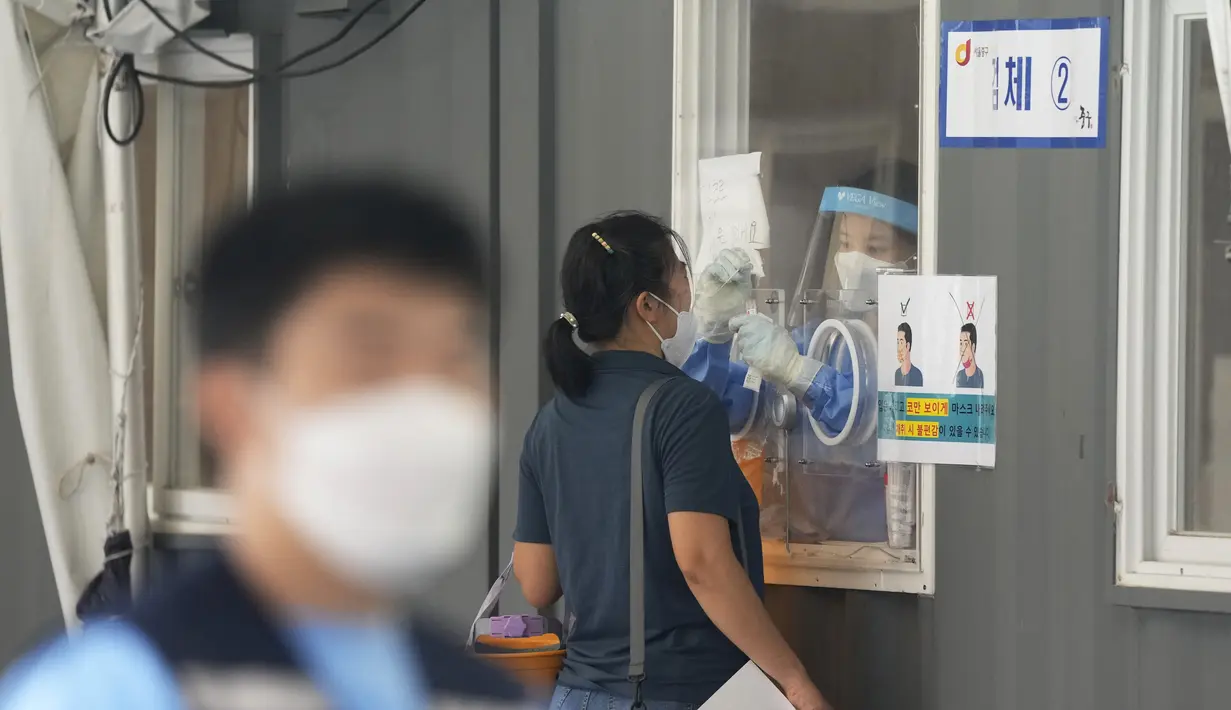 Pekerja medis yang mengenakan alat pelindung di sebuah bilik mengambil sampel wanita selama pengujian COVID-19 di tempat pengujian virus corona di Seoul, Korea Selatan, Rabu (1/9/2021). Korea Selatan pada hari Rabu melaporkan lebih dari 2.000 kasus virus corona baru. (AP Photo/Ahn Young-joon)