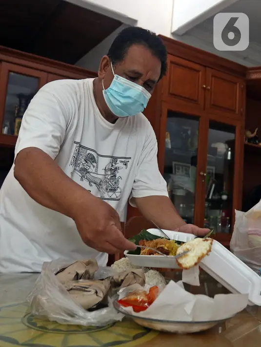 Suami NY, perempuan yang sedang melakukan isolasi mandiri karena terjangkit COVID-19, menyiapakan makanan untuk sang istri di kediamannya, Rabu (10/2/2021). (Liputan6.com/Herman Zakharia)
