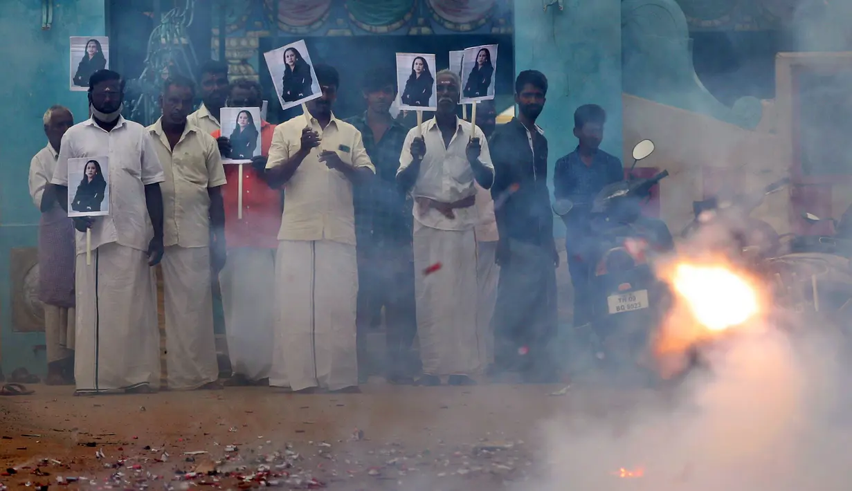 Warga desa menyalakan petasan sambil memegang plakat bergambar Wakil Presiden AS terpilih Kamala Harris menjelang pelantikan Harris di Thulasendrapuram, selatan Chennai, Tamil Nadu, India, Rabu (20/1/2021). Thulasendrapuram adalah kampung halaman kakek Harris dari pihak ibu. (AP Photo/Aijaz Rahi)