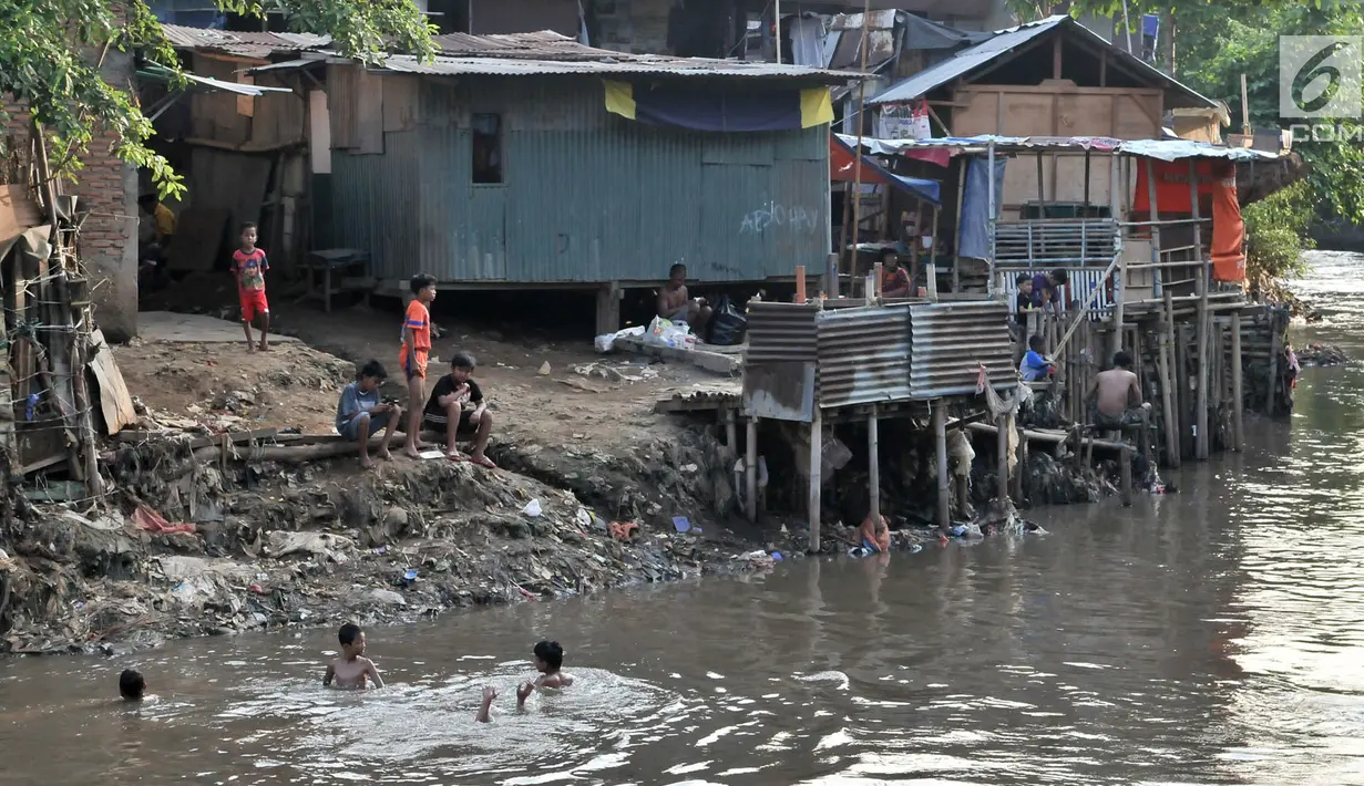 Anak-anak berenang di bawah jamban yang berada di bantaran Kali Ciliwung, Jakarta, Senin (19/11). Tak adanya akses sanitasi yang layak menyebabkan anak-anak menderita stunting. (Merdeka.com/Iqbal Nugroho)
