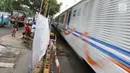 Kereta melintas di sebelah pintu perlintasan sebidang kereta api di Jalan Kebon Sereh, Jatinegara, Jakarta Timur, Senin (29/5). Penutupan pintu perlintasan itu bertujuan mengurai kemacetan serta mengurangi kecelakaan. (Liputan6.com/Immanuel Antonius)