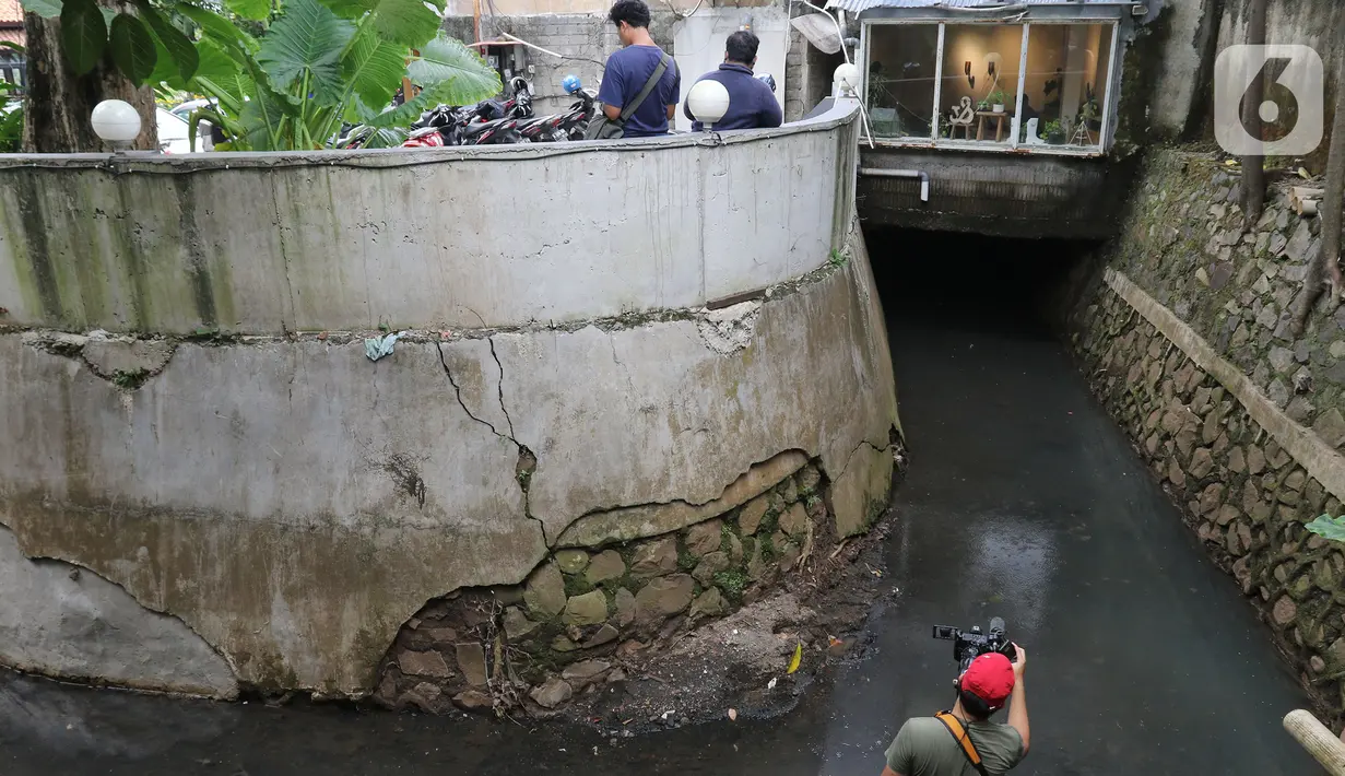 Seorang pria mengambil gambar saluran air yang di atasnya berdiri bangunan di Kemang Utara, Jakarta, Rabu (17/11/2021). Wakil Gubernur DKI Ahmad Riza Patria menegaskan pendirian bangunan yang melanggar tata ruang, akan ditindak sesuai prosedur yang berlaku. (Liputan6.com/Herman Zakharia)