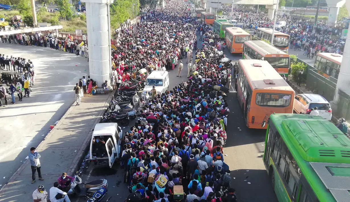 Pekerja migran dan anggota keluarga mereka menyerbu terminal bus Anand Vihar untuk pulang kampung selama pemberlakukan lockdown di New Delhi, Sabtu (28/3/2020). Ribuan orang meninggalkan New Delhi setelah pemerintah India memberlakukan lockdown untuk mencegah penyebaran COVID-19. (Bhuvan BAGGA/AFP)