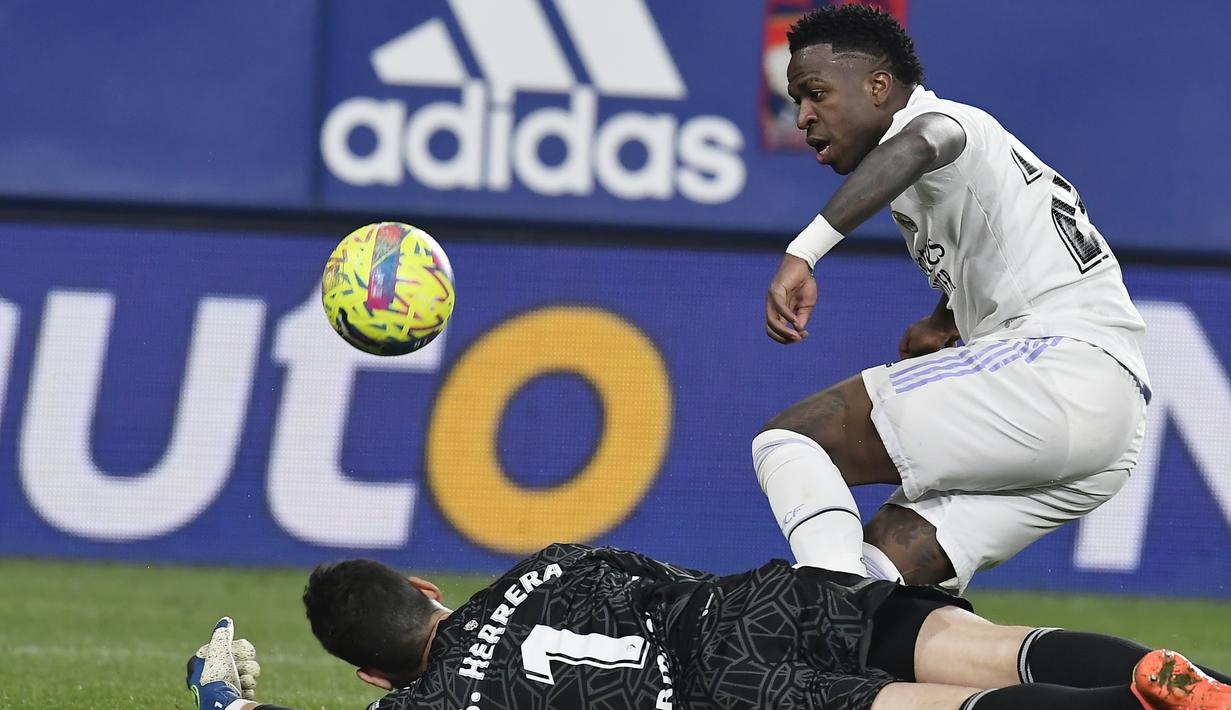 <p>Kiper Osasuna, Sergio Herrera menghalau bola tendangan penyerang Real Madrid, Vinicius Junior selama pertandingan lanjutan La Liga Spanyol di stadion El Sadar di Pamplona, Spanyol, Minggu (19/2/2023). Tambahan tiga angka membuat Madrid kini mengoleksi 51 poin. (AP Photo/Alvaro Barrientos)</p>