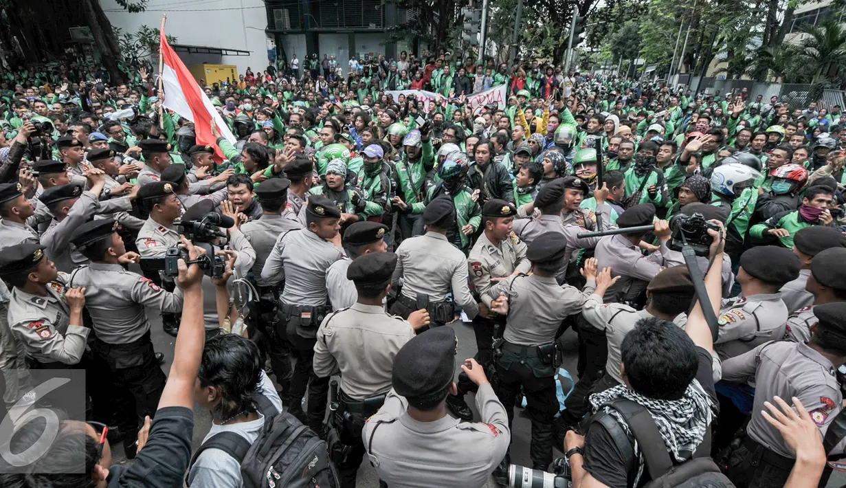 Massa driver Gojek terlibat aksi saling dorong dengan polisi saat demo ke kantor pusat mereka di Kemang, Senin (3/10). Ratusan pengemudi Gojek itu menuntut penghapusan sistem performa atau rating. (Liputan6.com/Yoppy Renato)