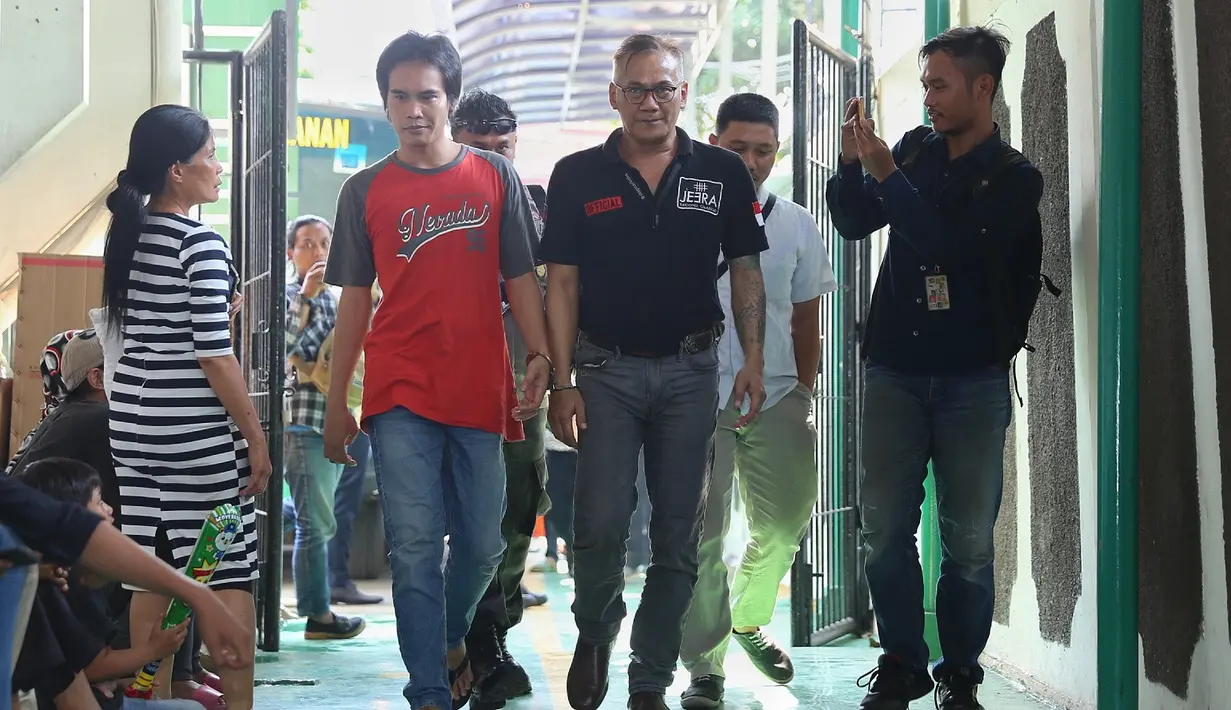 Terlihat tangan Tio Pakusadewo diborgol dengan tahanan lain. Tio berjalan memasuki ruang tunggu sambil menunggu jadwal sidang. (Nurwahyunan/Bintang.com)