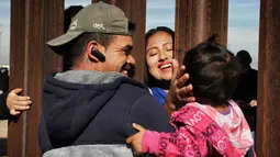Sebuah keluarga berkumpul di balik dinding perbatasan antara Meksiko dan Amerika Serikat di Ciudad Juarez, 10 Desember 2017. Mereka diberikan waktu tiga menit untuk bertemu keluarganya yang terpisahkan karena dinding perbatasan itu. (Herika MARTINEZ/AFP)