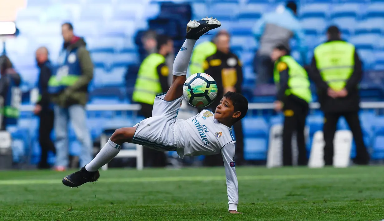 Anak Cristiano Ronaldo, Cristiano Ronaldo Jr melakukan tendangan salto usai pertandingan antara Real Madrid dan Atletico Madrid di stadion Santiago Bernabeu, Madrid (8/4). Anak Ronaldo melakukan tendangan salto meniru sang ayah. (AFP Photo/Gabriel Bouys)