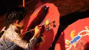 Salah satu anak memberikan hiasan gambar di atas payung kertas di Museum Layang-Layang, Jakarta, (27/9/2014). (Liputan6.com/Helmi Fithriansyah)