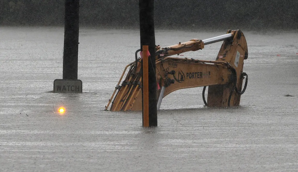 Ekskavator yang terbengkalai masih memiliki lampu peringatan yang berkedip-kedip karena tertelan air dari Sungai Hawkesbury yang banjir di Windsor, barat laut Sydney, New South Wales, Australia (22/3/2021).  (AP Photo/Rick Rycroft)