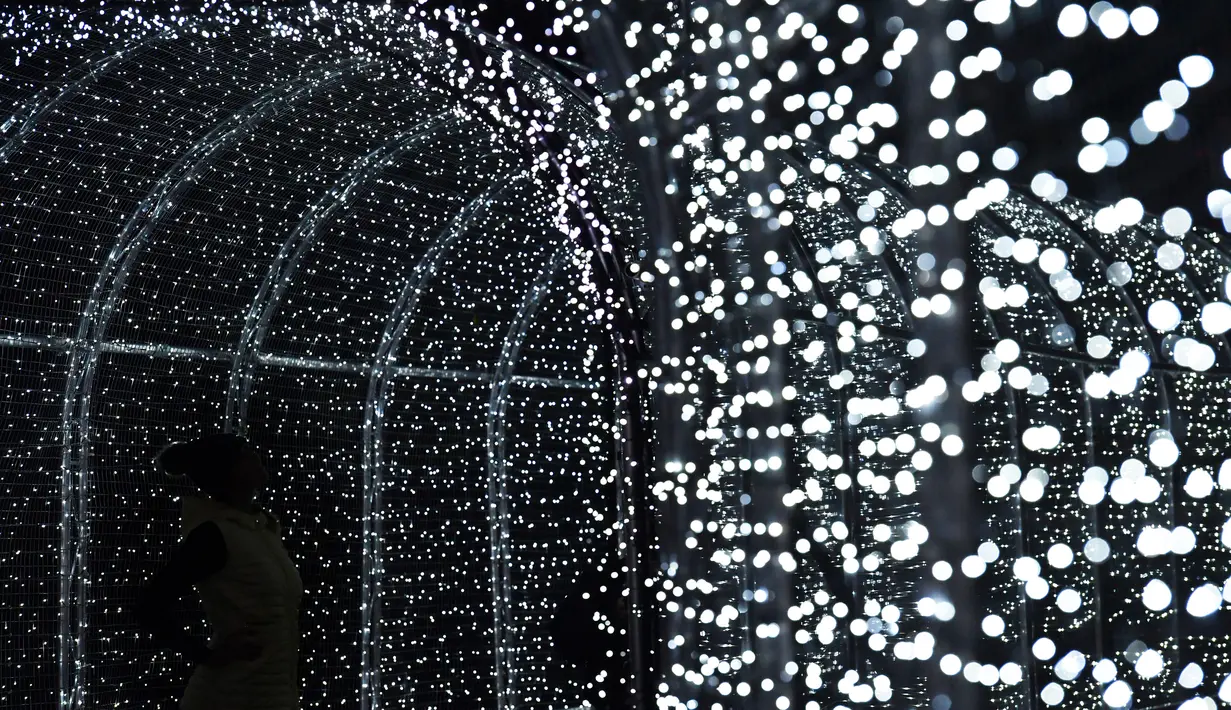 Sebuah terowongan yang dipenuhi cahaya lampu jelang perayaan Natal di Kew Gardens, London (21/11). Cahaya lampu yang menghiasi Kew Gardens ini menjadi daya tarik wisatawan. (AFP Photo/Ben Stansall)