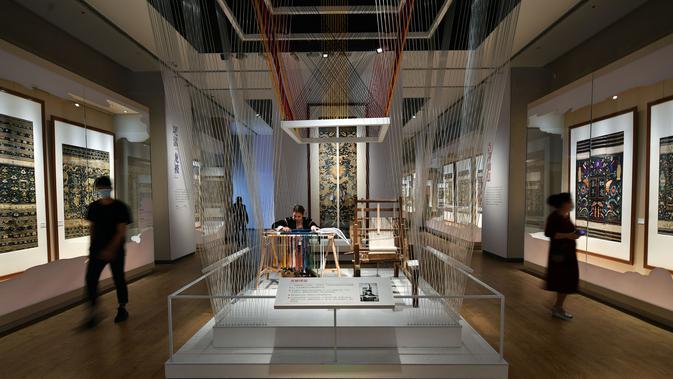 Orang-orang mengamati selimut quilt dengan pola naga dalam pameran selimut quilt di Museum Hainan di Haikou, Provinsi Hainan, China pada 13 November 2020. Pameran yang berlangsung sebulan penuh tersebut menampilkan 41 selimut quilt dengan bordir naga Li yang indah. (Xinhua/Guo Cheng)