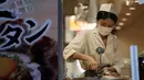 Seorang pegawai restoran yang memakai masker untuk membantu mencegah penyebaran virus corona menyiapkan hidangan untuk pelanggan di Tokyo, Kamis (10/9/2020). Ibukota Jepang mengonfirmasi lebih dari 270 kasus virus korona pada hari Kamis. (AP Photo / Eugene Hoshiko)