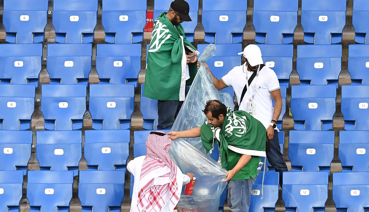 Suporter Arab Saudi memunguti sampah di tribun seusai laga melawan Uruguay pada pertandingan kedua Grup A Piala Dunia 2018 di Rostov Arena, Rostov-on-Don, Rabu (20/6). Kalah 0-1, Arab Saudi menjadi tim kedua yang tersingkir setelah Maroko (AFP/JOE KLAMAR)