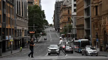 Pejalan kaki melintasi jalan yang biasanya padat dengan lalu lintas di kawasan pusat bisnis di Sydney, Rabu (30/12/2020). Pihak berwenang berupaya menekan klaster kasus virus corona Covid-19 yang terus bertambah di kota terpadat di Australia tersebut. (Saeed KHAN / AFP)