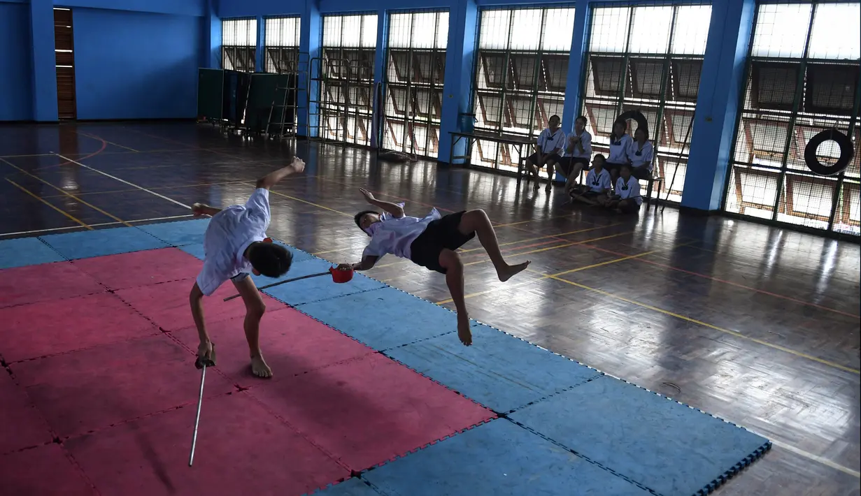 Dua siswa bertarung menggunakan pedang selama berlatih Krabi Krabong di sekolah Thonburee Woratapeepalarak, Thonburi, Bangkok (8/7/2019). Krabi Krabong merupakan seni bela diri Thailand yang dipersenjatai pisau dan perisai kayu yang terabaikan. (AFP Photo/Lillian Suwanrumpha)