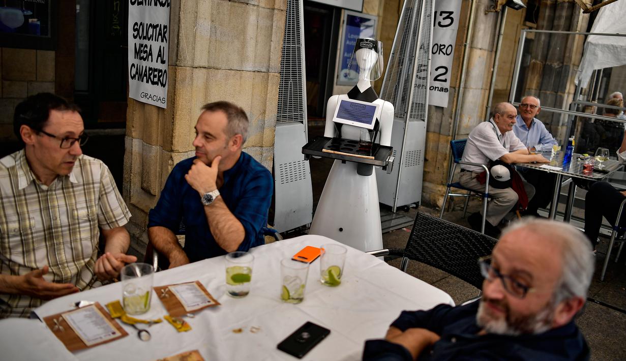 Sebuah robot yang dikenal sebagai "Alexia" melayani pengunjung sebuah bar di alun-alun Plaza del Castillo, di Pamplona, Spanyol pada 5 Juni 2020. Robot tersebut digunakan untuk mengurangi penyebaran virus corona Covid-19. (AP Photo/Alvaro Barrientos)