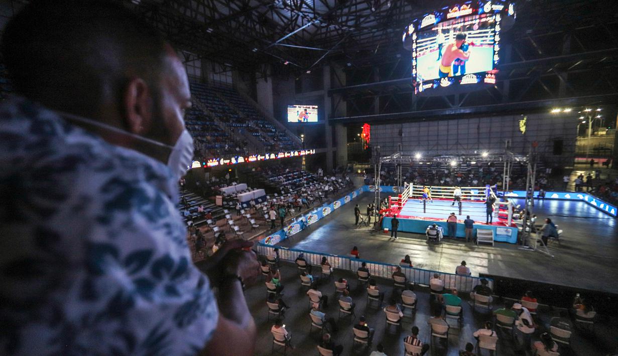 Penonton mengenakan masker saat melihat pertandingan tinju yang dipromotori oleh mantan juara dunia Rosendo Alvarez di Managua, Nikaragua pada 25 April 2020. Nikaragua merupakan salah satu dari sedikit negara yang kegiatan olahraga tetap berjalan di tengah pandemi Covid-19. (AP/Alfredo Zuniga)