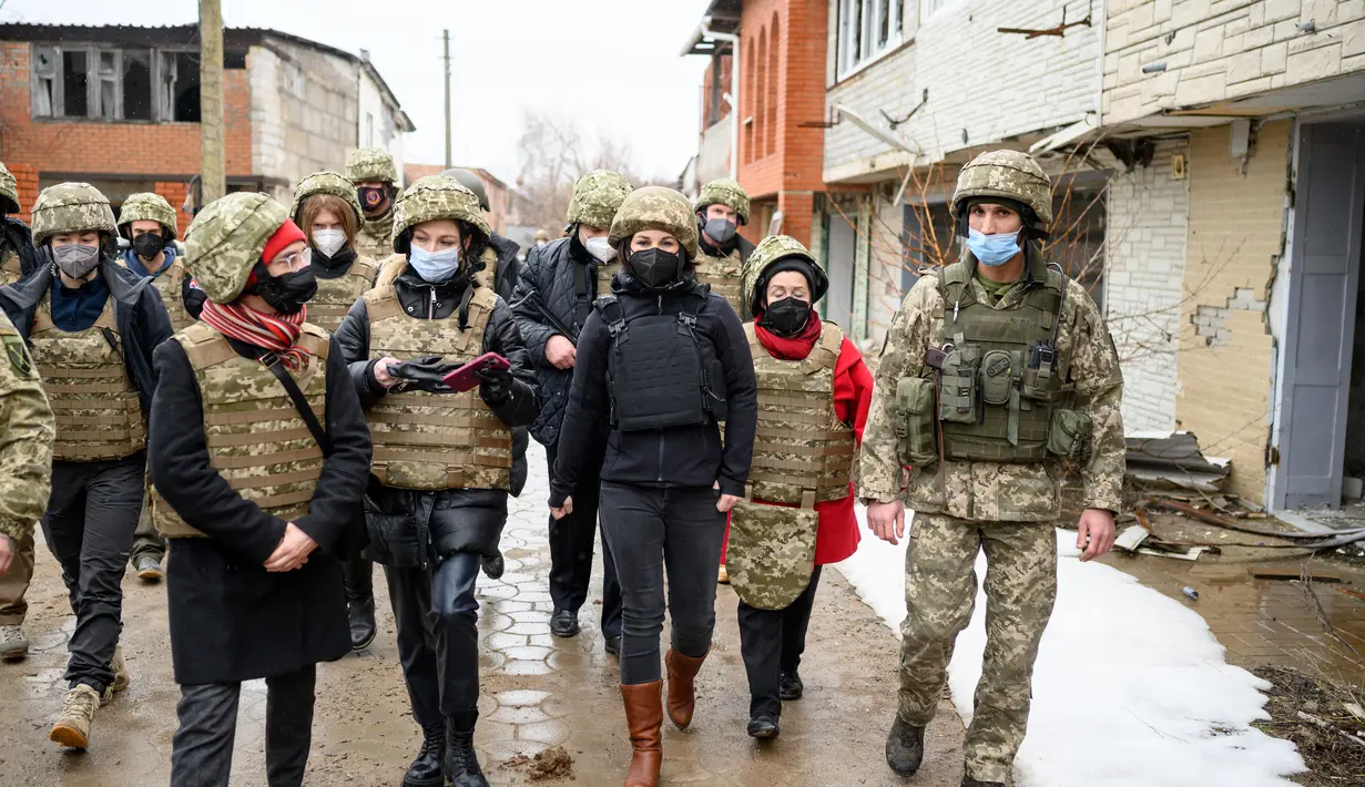 Menteri Luar Negeri Jerman Annalena Baerbock (keempat kanan) berjalan saat berkunjung di Shyrokyne, Wilayah Donetsk, Ukraina (8/2/2022). Menurut kantor berita Jerman DPA, tidak ada kekerasan yang terjadi selama kunjungan Annalena Baerbock. (AFP/Pool/Bernd von Jutrczenka)