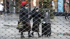 Dua biarawati terlihat berjalan dari balik pagar besi pusat perbelanjaan di Essen, Jerman, Senin (14/12/2020). Jerman melakukan lockdown nasional pada 16 Desember 2020 untuk memerangi pandemi COVID-19. (AP Photo/Martin Meissner)