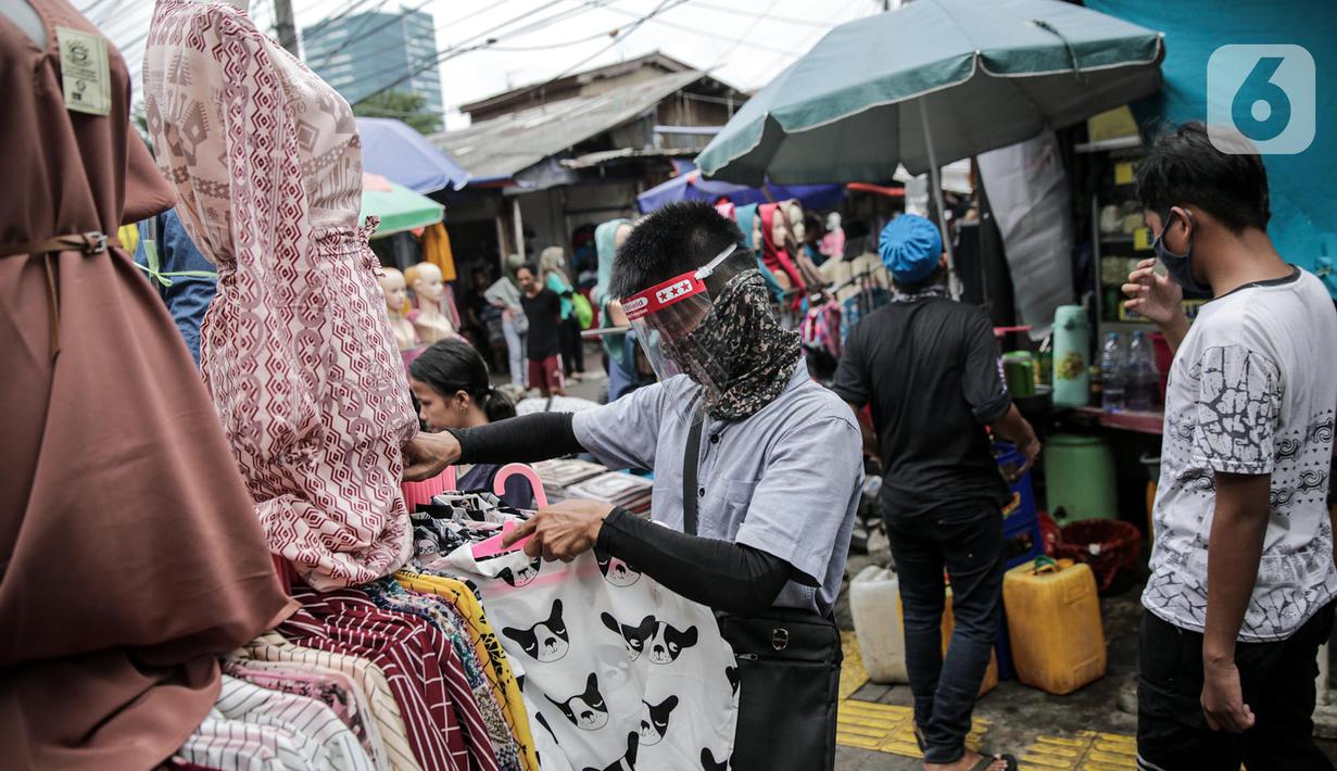 Pedagang menggunakan alat pelindung wajah (Face Shield) saat melayani pembeli di Kawasan Tanah Abang, Jakarta, Senin (18/5/2020). Penggunaan alat pelindung wajah itu sebagai upaya untuk melindungi diri saat berhubungan dengan pembeli dalam pecegahan penyebaran COVID-19. (Liputan6.com/Faizal Fanani)