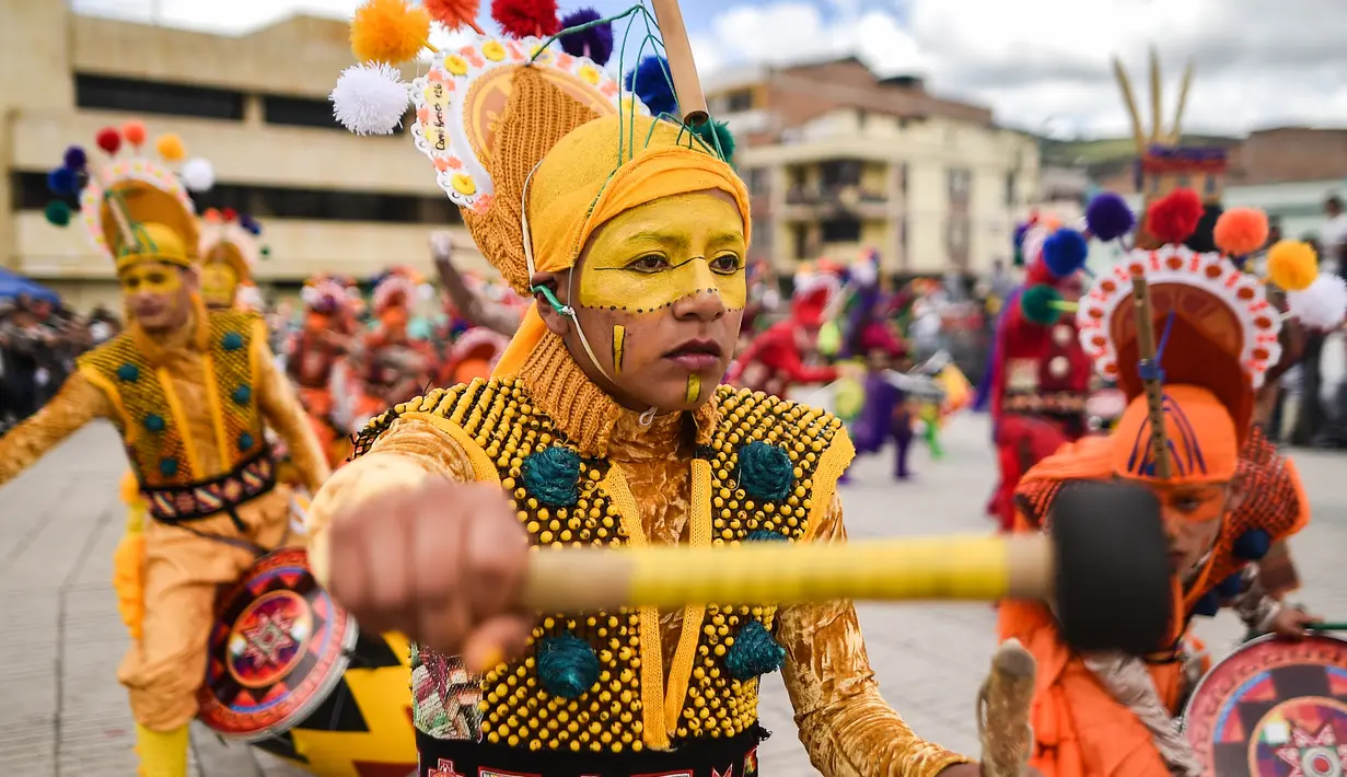 Peserta mengenakan kostum dan riasan memainkan alat musik saat parade Canto a la Tierra di Pasto, Kolombia (3/1). Acara ini dirayakan setiap tahunnya dari tanggal 2 sampai 6 Januari di kota Pasto. (AFP Photo/Luis Robayo)