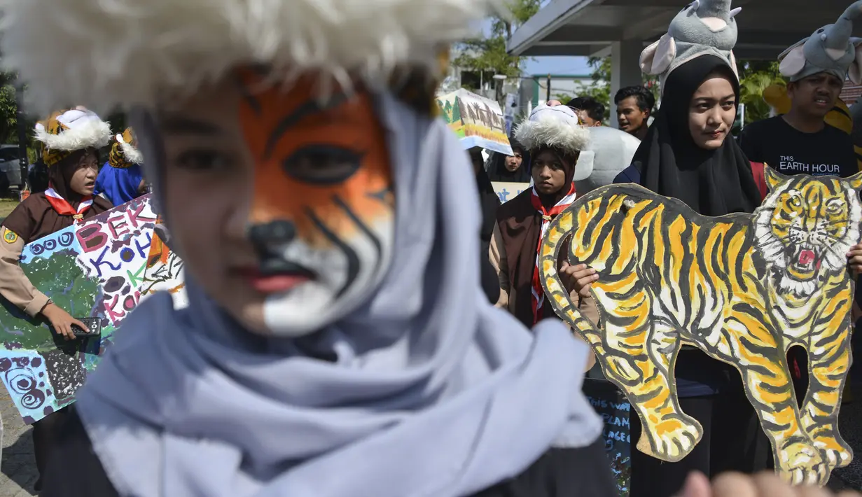 Sejumlah pelajar membawa gambar harimau saat melakukan aksi demonstrasi dalam peringatan Hari Bumi Sedunia di Banda Aceh (22/4). Mereka menyerukan penyelamatan empat satwa kunci yang terancam punah. (AFP Photo/Chaideer Mahyuddin)