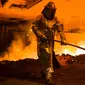 Seorang pekerja mengenakan pakaian pelindung mengambil cairan untuk membuat baja di Salzgitter, Jerman (22/3). Baja dibuat‎ dari hasil peleburan pasir besi, batu bara dan kapur dengan suhu di atas 1.000 derajat celciu‎s.  (AP Photo / Markus Schreiber)