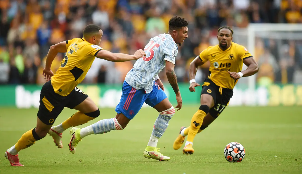 Striker Manchester United (MU) Jadon Sancho (tengah) ditantang oleh pemain Wolverhampton Wanderers Marcal (kiri) dan Adama Traore pada match day ketiga Liga Inggris di Stadion Molineux, Minggu (29/8/2021). MU menang tipis 1-0 lewat gol Mason Greenwood. (Oli SCARFF/AFP)