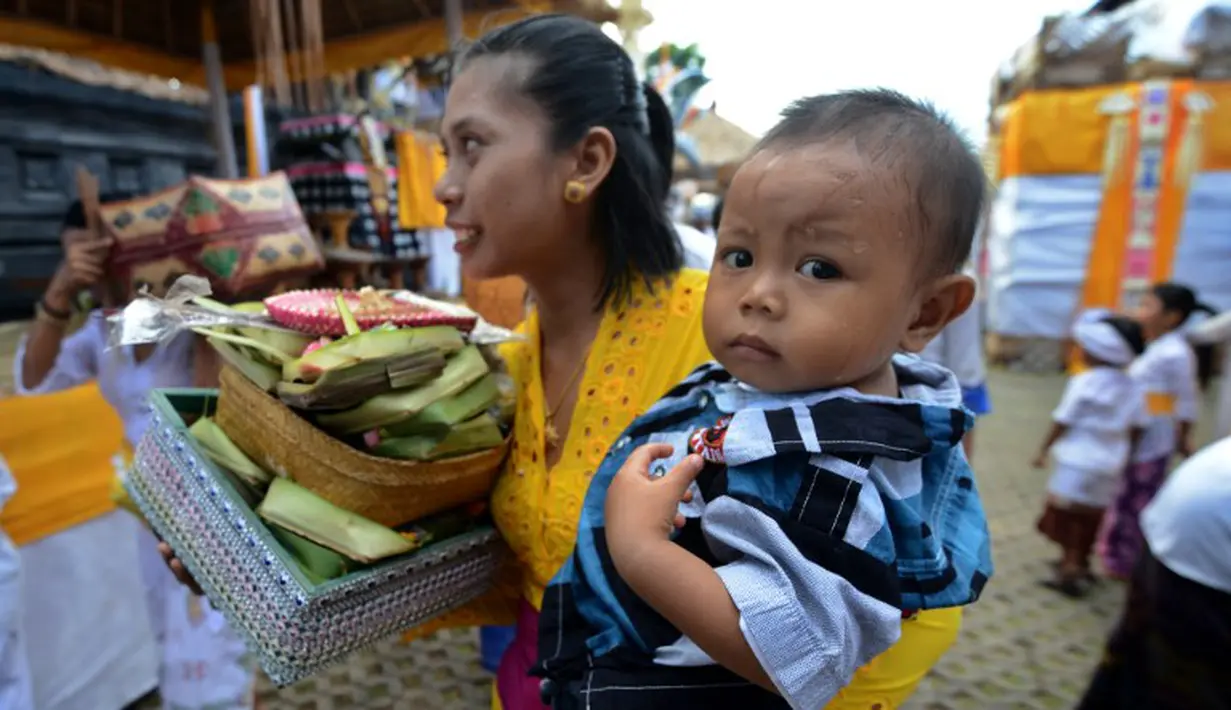 Seorang warga tampak membawa anaknya mendatangi pura untuk merayakan hari raya Galungan di Jimbaran, Bali, Rabu (21/5/14). (AFP PHOTO/Sonny Tumbelaka)