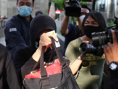 Wali Kota Banjar, Ade UU Sukaesih (tengah) menutupi wajah saat keluar area Gedung KPK, Jakarta, Rabu (12/8/2020). Ade UU Sukaesih diperiksa terkait proses penyidikan dugaan tindak pidana korupsi proyek infrastuktur pada dinas PUPR Kota Banjar TA 2012-2017. (Liputan6.com/Helmi Fithriansyah)