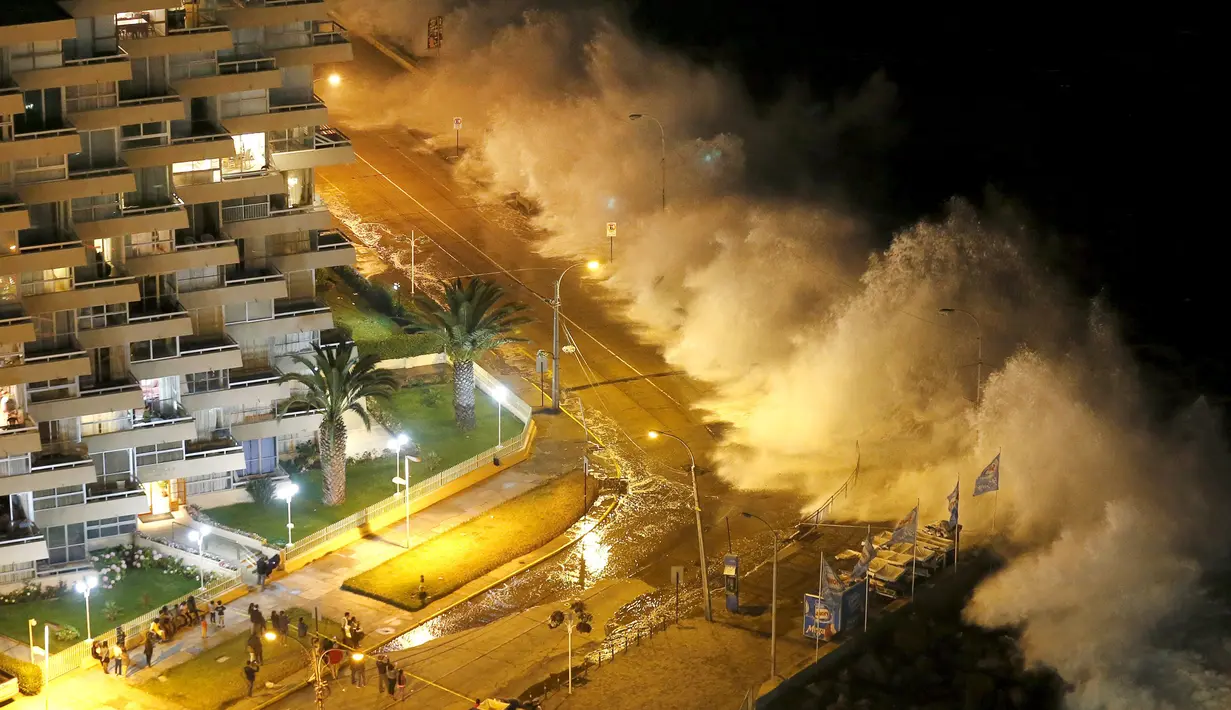 Sejumlah turis asik menonton ombak yang tinggi di pantai kota Vina del Mar, Chile,  (25/1).   Wisatawan sudah di himbau untuk menjauh dari bibir pantai karena ombak dan angin yang tinggi. (REUTERS / Rodrigo Garrido)