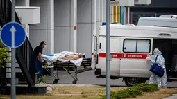 Petugas medis mengantar seorang pria menuju rumah sakit untuk pasien COVID-19 di pemukiman Kommunarka di luar Moskow, Rabu (30/6/2021). Rusia pada hari Rabu kembali melaporkan rekor kematian harian akibat virus Corona, dengan mencatat 669 kematian dalam 24 jam terakhir. (Dimitar DILKOFF/AFP)