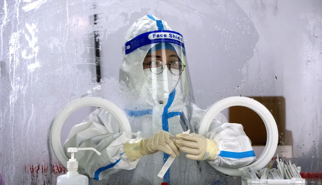 Seorang pekerja yang mengenakan pakaian pelindung menunggu untuk melakukan tes COVID-19 di tempat pengujian virus corona di Beijing, Rabu (6/7/2022). Lockdown dan pengujian massal berulang kali terjadi di China. Ini merupakan bagian dari kebijakan nol-Covid yang bertujuan untuk memberantas semua wabah. (AP Photo/Mark Schiefelbein)